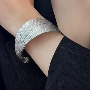 Polished silver wide textured multi-layer cuff bracelet on a model wearing black suit