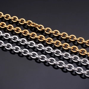 Polished gold and silver stainless steel O-link chains on a reflective black background