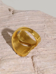 Detailed shot of irregular 18k gold-plated chunky ring on a light stone textured base