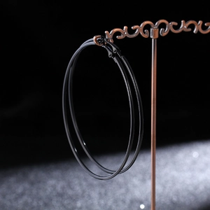 Close-up of large black metal hoop earrings on a vintage bronze jewelry stand