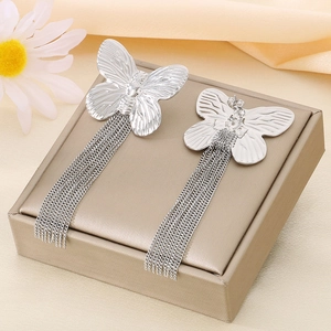 Elegant silver butterfly tassel earrings on a luxury display box with silk background