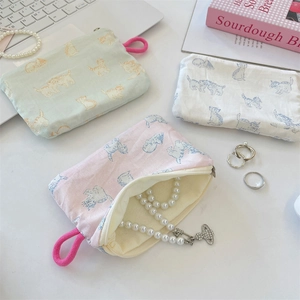 Detailed view of three cloth zipper pouches with cat prints for jewelry and headphones