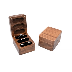 Macro view of walnut wood jewelry box featuring three slots with black sponge padding