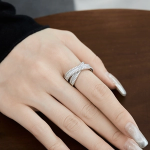Bague croisée en argent sterling S925 sertie de zircons portée sur un fond en bois