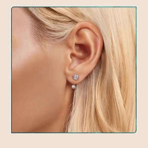 Detailed view of silver stud earrings with sparkling moissanite and a small white pearl