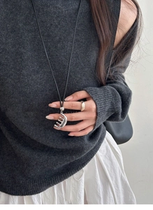 Detail of silver half-moon pendant necklace on black cord with a minimalist ring