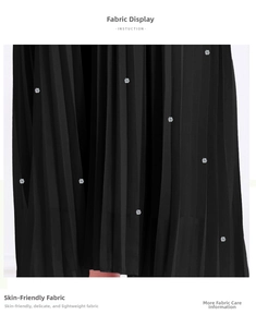Détail du tissu plissé noir avec des fleurs pailletées argentées pour une robe de luxe