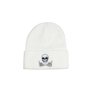 Close-up of white knit beanie featuring skull and skeletal hands embroidery detail