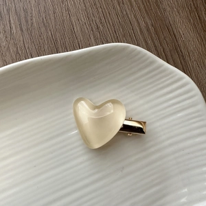 Detail of cream jelly heart hair clip with gold metal base on a ceramic plate