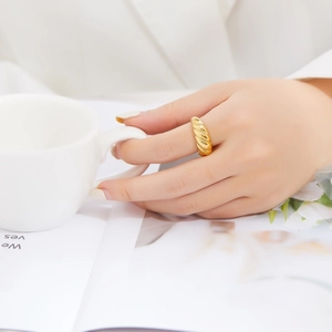 Close-up of a gold croissant dome ring with a twisted texture worn by a model