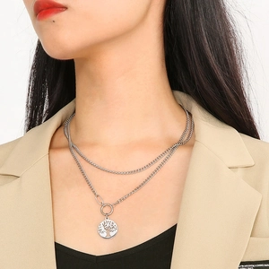 Detail of double-layer silver Cuban chain necklace with Tree of Life pendant on a model