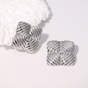 Vue détaillée des boucles d'oreilles carrées argentées avec texture ondulée en métal
