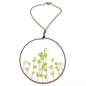 Detailed view of handmade copper wire-wrapped tree of life pendant with green crystal stones