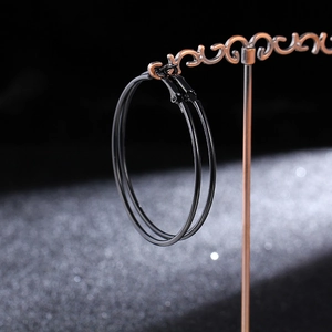 Macro side view of sleek black hoop earrings on a vintage bronze jewelry display stand