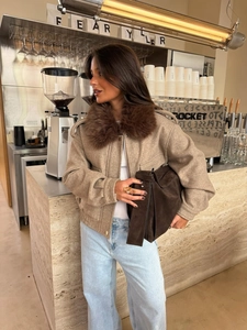 Detail of light camel cropped jacket with premium faux fur collar in a cafe setting