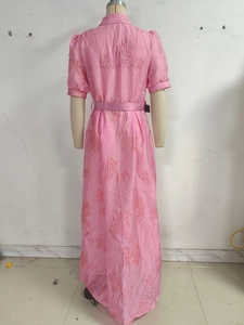 Close-up of elegant pink jacquard floral fabric and waist tie detail on the dress
