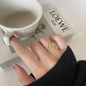 Detail of a golden twisted chain ring on a hand with minimalist lifestyle background