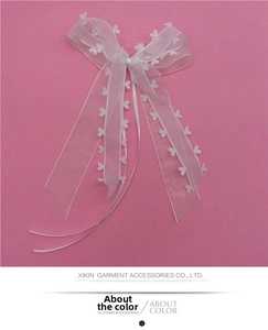 Detailed view of white organza ribbon bow with heart cutouts for wedding car decoration