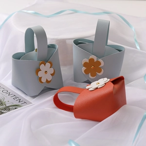 Close-up of PU leather wedding favor bags with floral decor and gold rivets