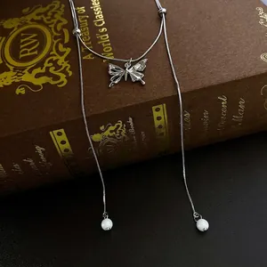 Elegante Schmetterlings-Zirkonia-Halskette mit Perlenquasten auf Vintage-Buch