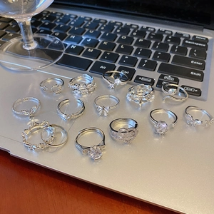 Collection of silver zircon rings with heart, butterfly and snake motifs on a laptop