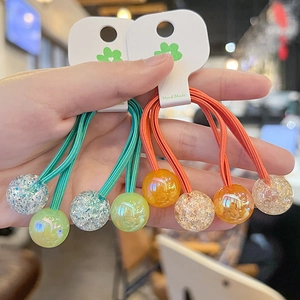Detail of colorful resin bead hair ties in green, blue, orange and yellow with hand-made label