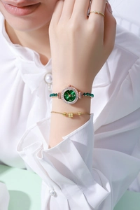 Close-up of a gold ladies' watch with green dial and matching beaded bracelet on a wrist