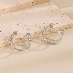 Detail of silver triple-layered C-shape twisted earrings on a stone platform