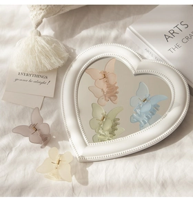 Detail of matte butterfly hair clips in pastel colors on a soft textured background