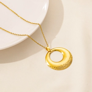 Macro view of gold pendant with hammer-textured finish on a minimalist fine chain