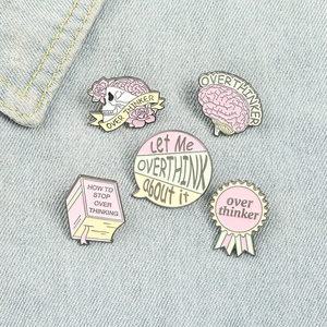 Macro detail of five pastel enamel pins on denim, featuring skull and brain themes