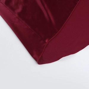 Detailed close-up of the smooth red satin dress hem with fine stitching and silk gloss