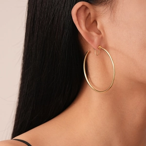 Close-up of a large minimalist gold geometric hoop earring worn by a model in profile