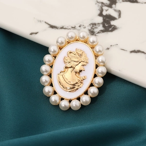 Close-up of vintage golden cameo brooch with white portrait relief and pearl borders