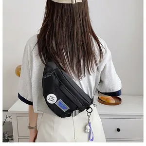 Detail of black nylon chest bag showing fashion badges and astronaut pendant on model