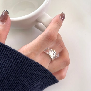 Irregular silver ring with gold dots texture shown on model finger in lifestyle setting