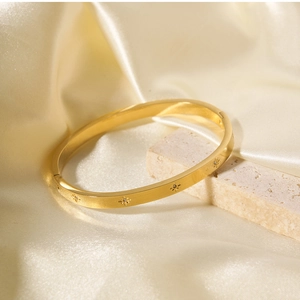 Detail of 18k gold plated stainless steel bangle with sunburst engravings and small crystals