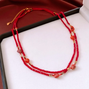 Close-up of double-layer red glass beaded necklace with golden metal accents and agate beads