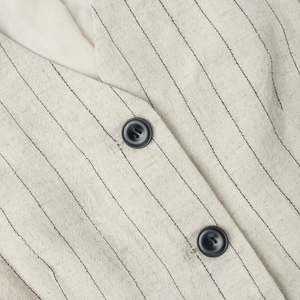 Macro detail of oatmeal striped vest featuring natural linen texture and black buttons