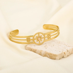 Detail of a gold-plated cuff bracelet featuring a bohemian floral design and a moonstone center
