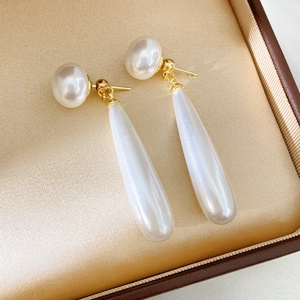 Detailed macro view of teardrop pearl earrings on golden silk lining luxury box