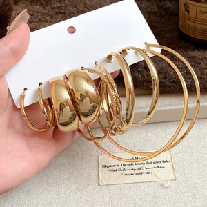 Close-up of gold chunky hoop earrings set with vintage texture on knitted background