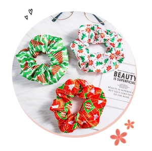 Detailed close-up of three satin Christmas scrunchies with festive snowflake and tree patterns