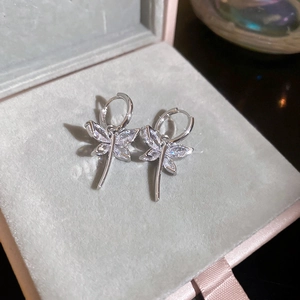 Macro shot of silver dragonfly earrings with cubic zirconia on grey velvet