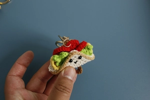 Close-up of handmade crochet taco keychain with cute smiling face and golden metal ring