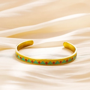 Gold-plated open cuff bracelet with colorful geometric triangle patterns on beige fabric