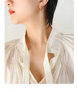 Close-up of interlocking gold and silver metallic hoops earrings on model with white shirt