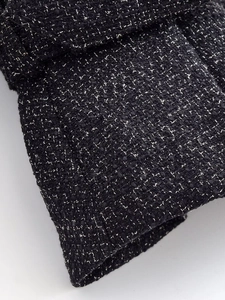 Detailed close-up of premium black and silver tweed fabric with intricate woven textures
