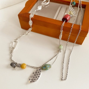 Close-up of Bohemian necklace with rustic wood beads and ceramic charms on a wooden box