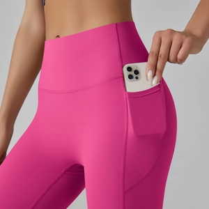 Macro shot of high-waist yoga leggings featuring functional side pocket and rosy red fabric